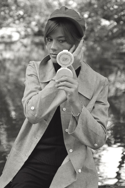 The French singer Françoise Hardy arranging her hair with the help of a handmirror, leaning against a wooden fence on the banks of a small lake in the gardens of Milan; the singer is in Italy for the resumption of the filming of 'Grand Prix' by John Frankenheimer, her third acting experience. Milan, summer 1966. (Photo by Mario De Biasi/Mondadori Portfolio via Getty Images)